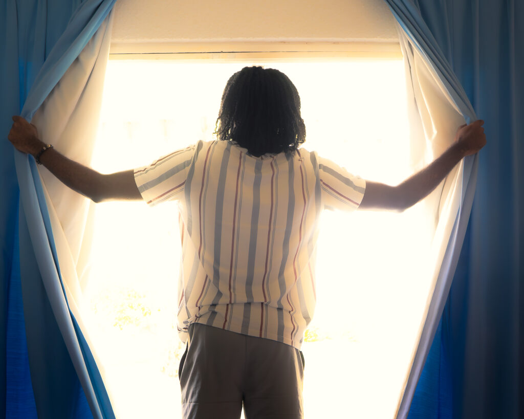 Guest opening the curtains to morning light in an apartment at Plum Tree Club Barbados