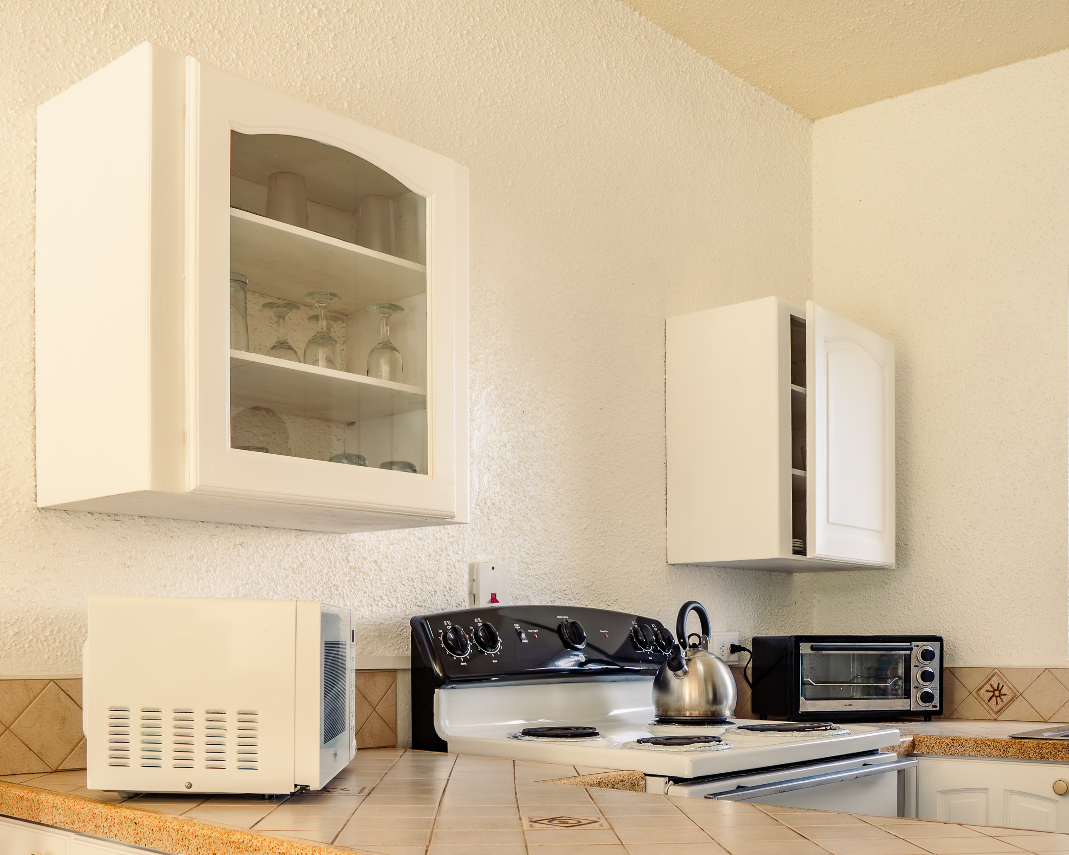 Fully equipped kitchen in a self-catering apartment at Plum Tree Club Barbados, with microwave, hob and toaster oven