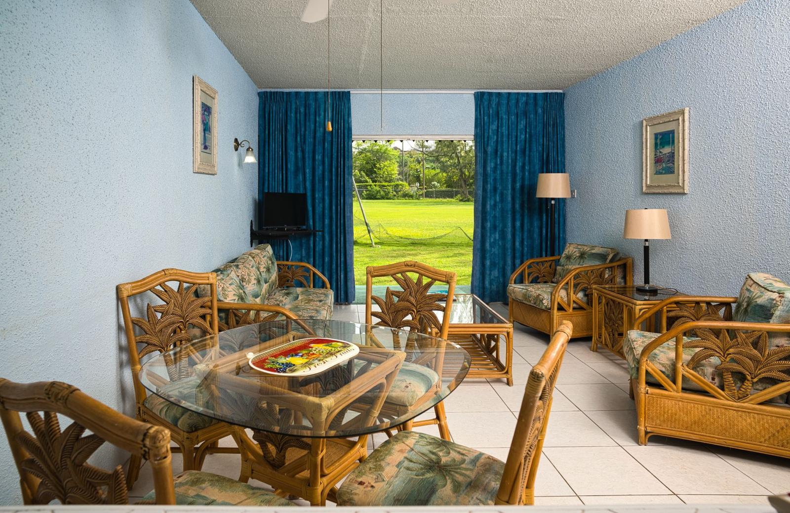 Living and dining area of an apartment at Plum Tree Club with the curtains open onto Rockley Golf Course