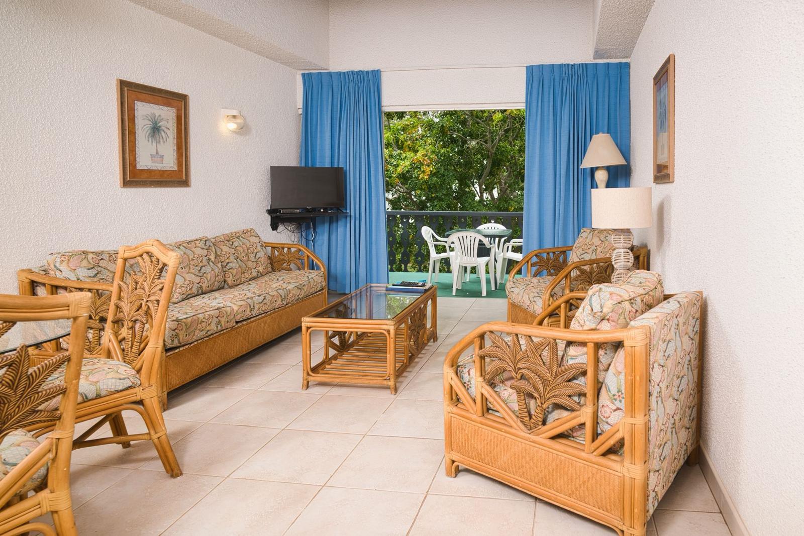 Apartment living room at Plum Tree Club with sofa seating and patio doors onto the garden